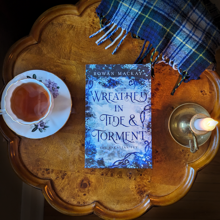 image of Wreathed in Tide & Torment paperback with a teacup and candle